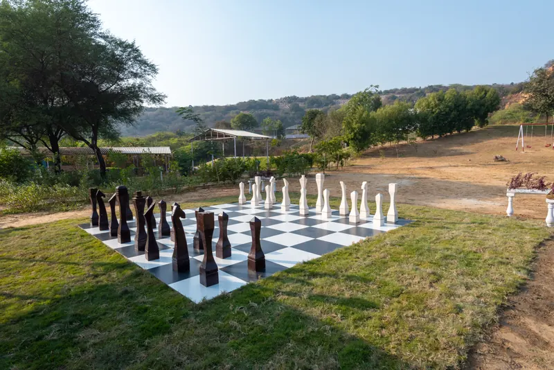 An outdoor chess board with oversized pieces beside the gardens