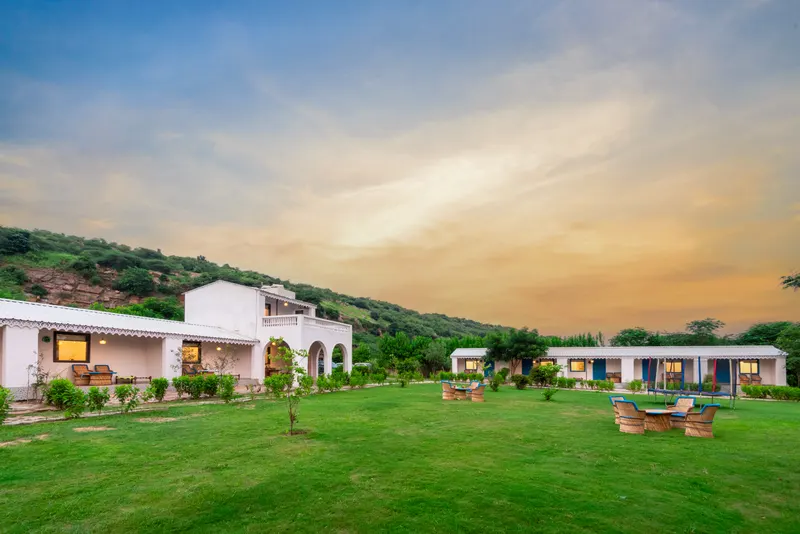 Farm Aravalia’s lawn and hill-view rooms beneath the Aravalli hills