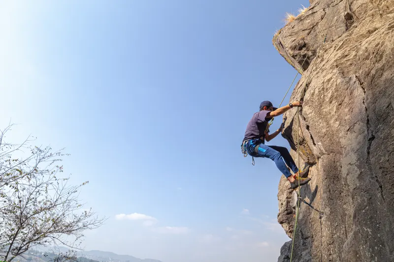A visitor rock climbing with equipment near Farm Aravalia