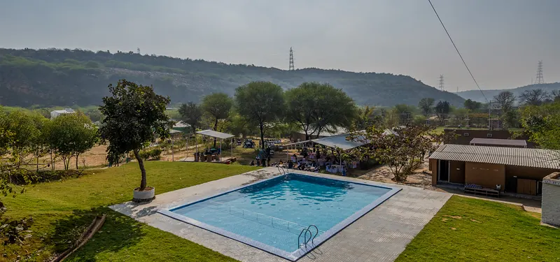 The swimming pool overlooking the green hills at Farm Aravalia