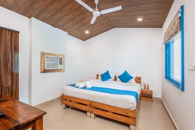 A Hill View Deluxe Room with a wooden bed and blue-framed window